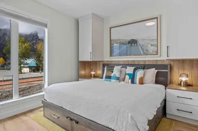 a bedroom with a large bed and two windows at Scenic Views in a Luxurious Townhouse in Canmore