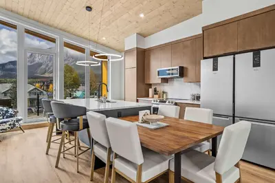 a kitchen with a wooden table and white chairs at Scenic Views in a Luxurious Townhouse in Canmore