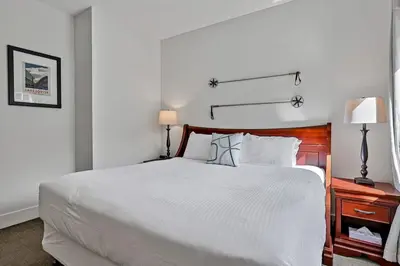 a white bedroom with a large bed and a desk at Classic Hideaway Elegant 2BD 2BTH in Canmore