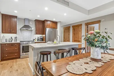 a kitchen with a wooden table with a vase of flowers at Alpine Serenity in Canmore in Canmore