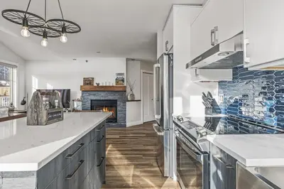 a kitchen with white counters and a fireplace at Spectacular Rocky Mountain Views 3BD in Canmore