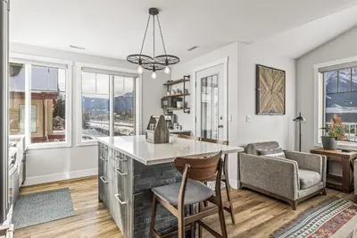a kitchen with a counter and chairs and windows at Spectacular Rocky Mountain Views 3BD in Canmore