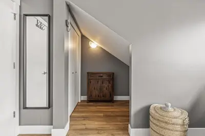 a hallway with a staircase with a mirror and a wooden floor at Spectacular Rocky Mountain Views 3BD in Canmore
