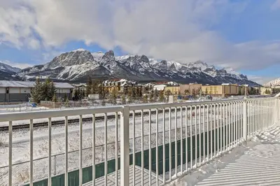a white fence with snowy mountains in the background at Spectacular Rocky Mountain Views 3BD in Canmore