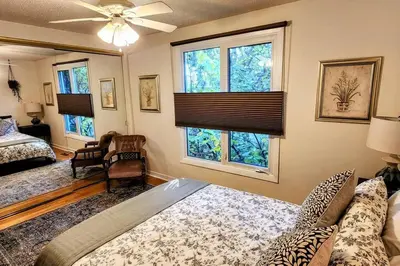 a bedroom with a bed and a couch and windows at Trendy Glenora , Sleeps 10 , Downtown & River Valley adjacent , Jacuzzi tub! in Edmonton