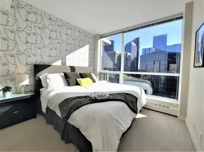 a bedroom with a bed and a large window at Luxury Condo by River with City Views in Calgary