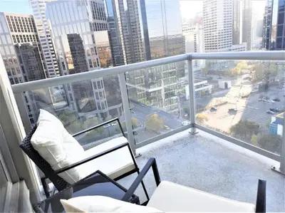 a balcony with a chair and a couch on a building at Luxury Condo by River with City Views in Calgary