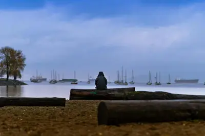a person sitting on a dock looking at the water at Stunning Skyline Views in a Cozy and Stylish Abode in Vancouver