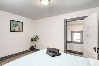 a white bedroom with a bed and a mirror at Oakwoods 1BR Suite in Bankview in Calgary