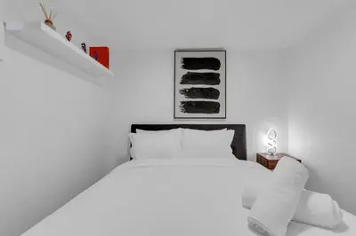 a white bedroom with a bed and a staircase at Luxury Suite, Steps to Calgary DT, River, Hospital in Calgary