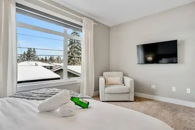 a bedroom with a bed and a tv and a chair at Luxury Cityscape Retreat with Hot Tub in Calgary