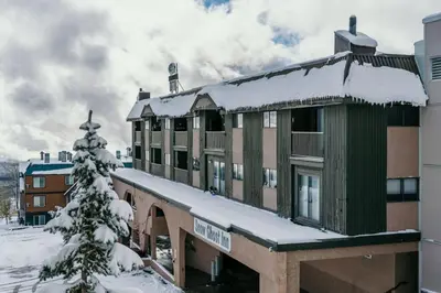 a building covered in snow with a christmas tree at The Lifty Ski-In Ski-Out Studio, Pool and Gym in Big White