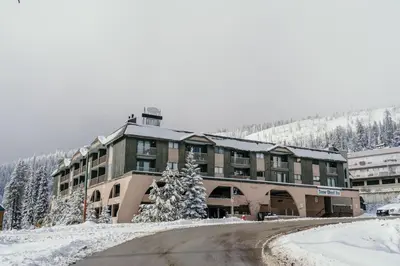 a large building in the snow with a road in front at The Lifty Ski-In Ski-Out Studio, Pool and Gym in Big White
