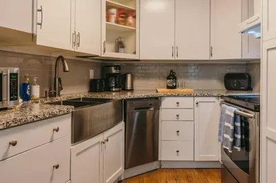 a kitchen with white cabinets and stainless steel appliances at The Lifty Ski-In Ski-Out Studio, Pool and Gym in Big White