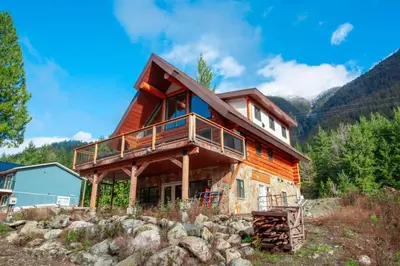 a log cabin with a wrap around deck on a mountain at Douglas Fir Retreat, Mtn Views and Expansive Deck in Sunshine Valley