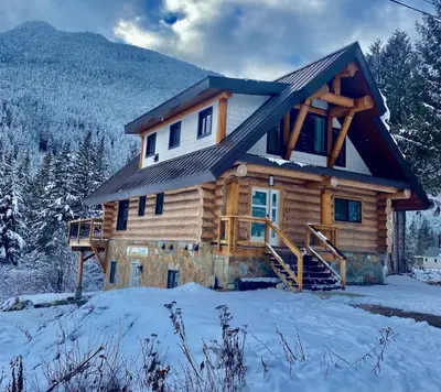 a log cabin in the woods in the snow at Douglas Fir Retreat, Mtn Views and Expansive Deck in Sunshine Valley