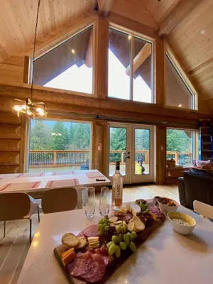a table with a plate of meat and wine glasses at Douglas Fir Retreat, Mtn Views and Expansive Deck in Sunshine Valley