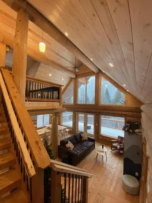 a living room with a staircase in a wooden house at Douglas Fir Retreat, Mtn Views and Expansive Deck in Sunshine Valley