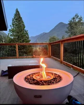 a fire pit on a deck with mountains in the background at Douglas Fir Retreat, Mtn Views and Expansive Deck in Sunshine Valley