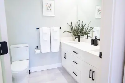 a white bathroom with a toilet and a sink at The Luna, New Penthouse w Patio, Lake and Mtn Views in Harrison Hot Springs