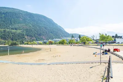 a beach with people laying on the sand at Echo Beach, 2 Bed, Lake View and Walkable to Beach in Harrison Hot Springs