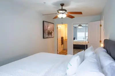 a bedroom with a white bed with a ceiling fan at Echo Beach, 2 Bed, Lake View and Walkable to Beach in Harrison Hot Springs