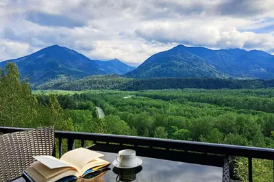 a book on a table with a view of mountains at EmeraldRidge Retreat - 180 Degree Amazing View & Firepit & BBQ in Chilliwack