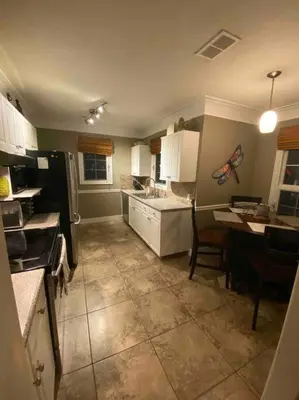 a kitchen with white cabinets and a table and a counter at Walk to the beaches and the restaurants downtown! in Kelowna