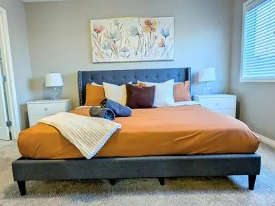 a bedroom with a large bed with orange sheets and pillows at A Slice of Heaven in Airdrie by EaglesWingsHomes1 in Airdrie