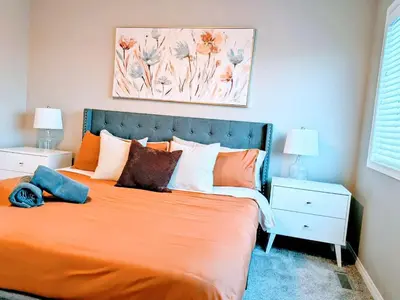 a bedroom with a bed with an orange bedspread at A Slice of Heaven in Airdrie by EaglesWingsHomes1 in Airdrie
