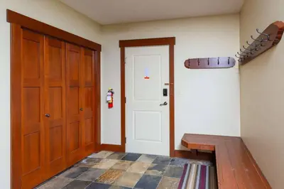 a room with a door and a bench and a rug at Stonegate Resort Unit A104 in Big White