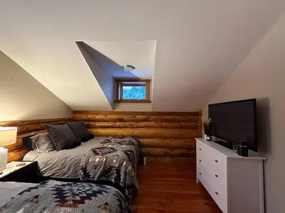 a bedroom with two beds and a flat screen tv at Ryders Lodge, Log Home in Edgewater, BC in Radium Hot Springs