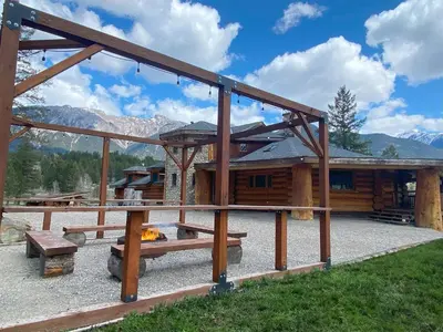 a log cabin with a fire in front of it at Ryders Lodge, Log Home in Edgewater, BC in Radium Hot Springs