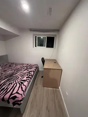 a bedroom with a bed and a desk and a window at Sam Estates in Calgary