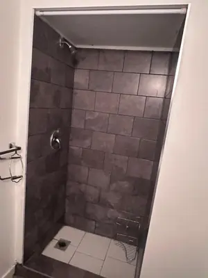 a bathroom with a shower with a tiled floor at Sam Estates in Calgary