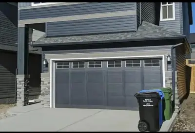 a garage door with a garbage can in front of a house at Lovely 2Bd 1Bth suite Free pking separated HVAC in Calgary