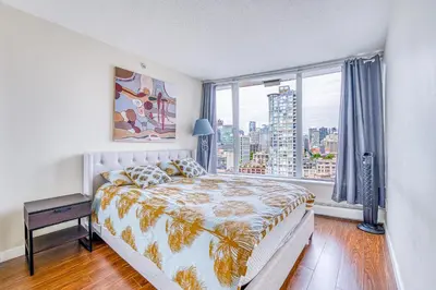 a bedroom with a bed and a large window at Great Ocean Mountain & City views with one free parking in Vancouver