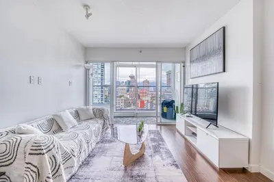 a living room with a couch and a large window at Great Ocean Mountain & City views with one free parking in Vancouver