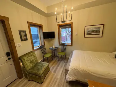 a bedroom with a bed and a chair and a table at Located in Downtown Whitehorse - Basekamp in Whitehorse