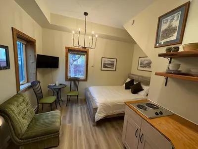 a bedroom with a bed and a living room at Located in Downtown Whitehorse - Basekamp in Whitehorse
