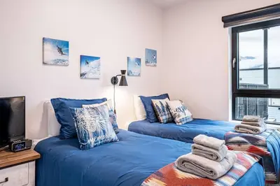 two blue beds in a room with a tv at Alpine Retreat by Revelstoke Vacations in Revelstoke