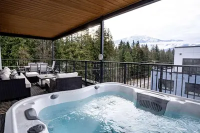 a jacuzzi tub on a balcony with a view at Alpine Retreat by Revelstoke Vacations in Revelstoke