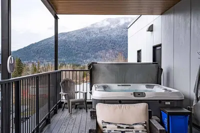 a hot tub on a balcony with a view of a mountain at Alpine Retreat by Revelstoke Vacations in Revelstoke