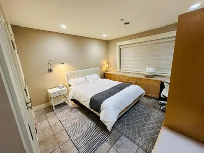 a bedroom with a bed and a desk and a window at Cozy Home in Dunbar in Vancouver