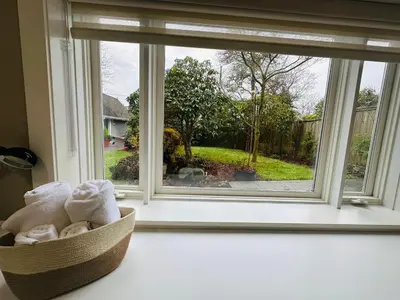 a basket of towels sitting in front of a window at Cozy Home in Dunbar in Vancouver