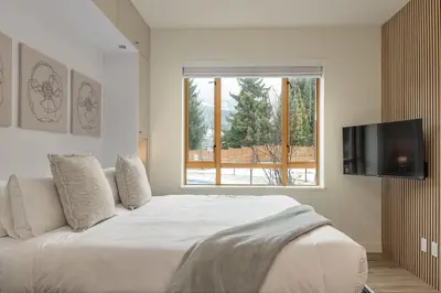 a bedroom with a white bed and a window at Newly Renovated KING BED STUDIO in the Village in Whistler