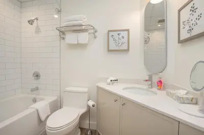 a white bathroom with a toilet and a tub and a sink at Newly Renovated KING BED STUDIO in the Village in Whistler