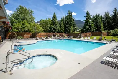 a large swimming pool with chairs around it at Newly Renovated KING BED STUDIO in the Village in Whistler