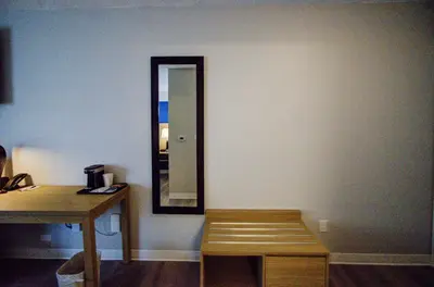 a mirror on a wall with a table and a bench at Baymont by Wyndham Gold River in Gold River