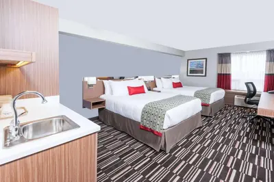 a hotel room with two beds and a sink at Microtel Inn & Suites by Wyndham Fort Saint John in Fort Saint John